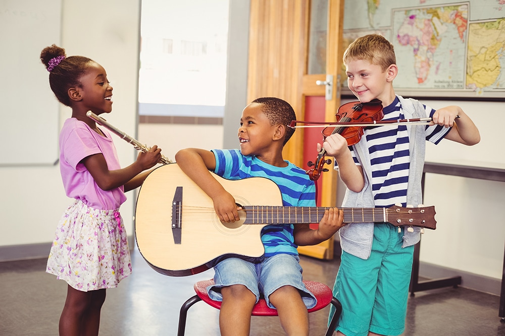 Smiling kids playing guitar, violin, flute in classroo